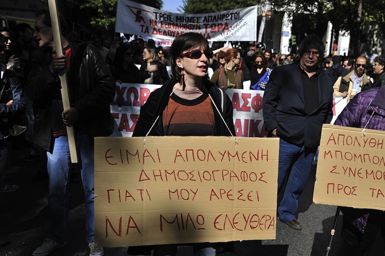 A Greek journalist carries a placard, re