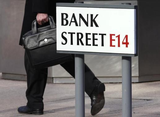 A worker passes a sign for Bank Street in the Canary Wharf financial district in London