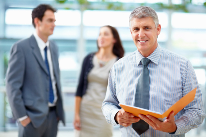 Happy business man holding file folder with colleagues in background