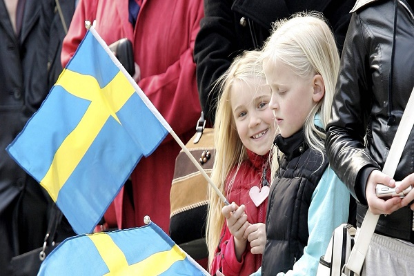STOCKHOLM, SWEDEN - APRIL 30:  Young girls wave Swedish flags during  the changing of the guard on H.M. King Carl XVI Gustaf of Swedens 60th birthday at the Stockholm Royal Palace on April 30, 2006 in Stockholm, Sweden.  (Photo by Chris Jackson/Getty Images)