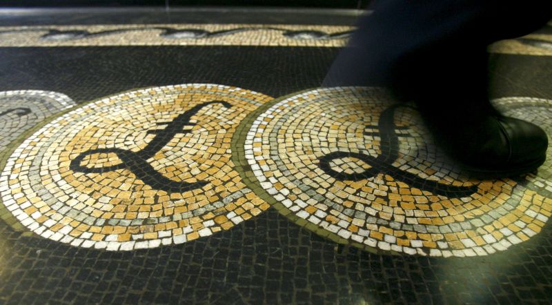 An employee is seen walking over a mosaic of pound sterling symbols set in the floor of the front hall of the Bank of England in London, in this March 25, 2008 file photograph.  REUTERS/Luke MacGregor/Files