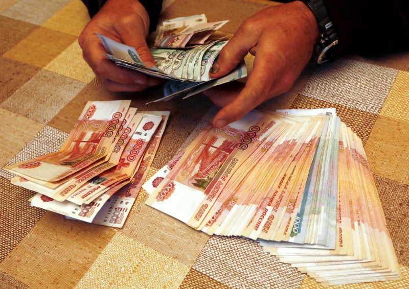 A local businessman, the owner of a tourist camp, counts Russian roubles earned during the weekend at a tourist base outside the Siberian city of Krasnoyarsk, Russia, August 9, 2015. Russia's largest gas producer Gazprom beat expectations with a 71 percent jump in first-quarter net profit after weakness in the rouble more than compensated for a drop in sales volumes to Europe. Gazprom's prices for gas sold to Europe are linked to the price of oil, but a time lag of several months means that its sales in the three months to March 31 were at prices pegged to oil at almost twice its January level of around $50 a barrel. Picture taken August 9, 2015. REUTERS/Ilya Naymushin