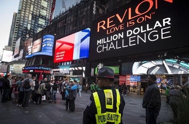 A Public Safety officer keeps watch as people stand in front of  a billboard owned by Revlon that takes their pictures and displays them in Times Square in the Manhattan borough of New York October 13, 2015. Cosmetics company Revlon switched on its "Kiss Cam" in New York's Times Square on Tuesday, four days after the interactive billboard went dark over complaints that it was attracting gropers. REUTERS/Carlo Allegri - RTS4CDM