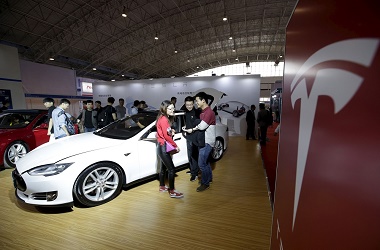 Visitors stand next to a Tesla Model S car during the Auto China 2016 in Beijing