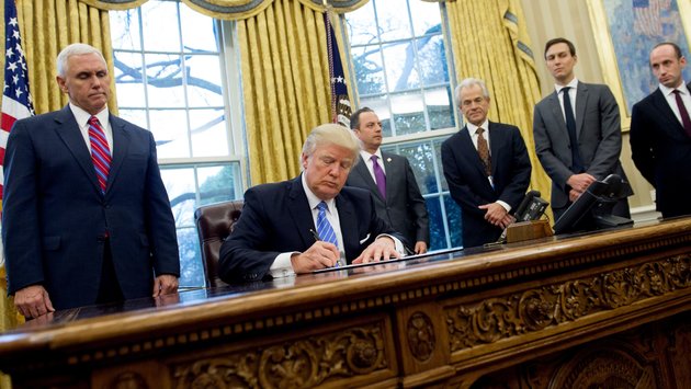 US President Donald Trump signs an executive order in the Oval Office of the White House in Washington, DC, January 23, 2017. Trump on Monday signed three orders on withdrawing the US from the Trans-Pacific Partnership trade deal, freezing the hiring of federal workers and hitting foreign NGOs that help with abortion. / AFP / SAUL LOEB (Photo credit should read SAUL LOEB/AFP/Getty Images)